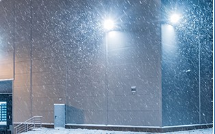 A wall pack lighting a building through snow